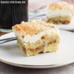 Close up view of a cinnamon roll poke cake on a white plate.