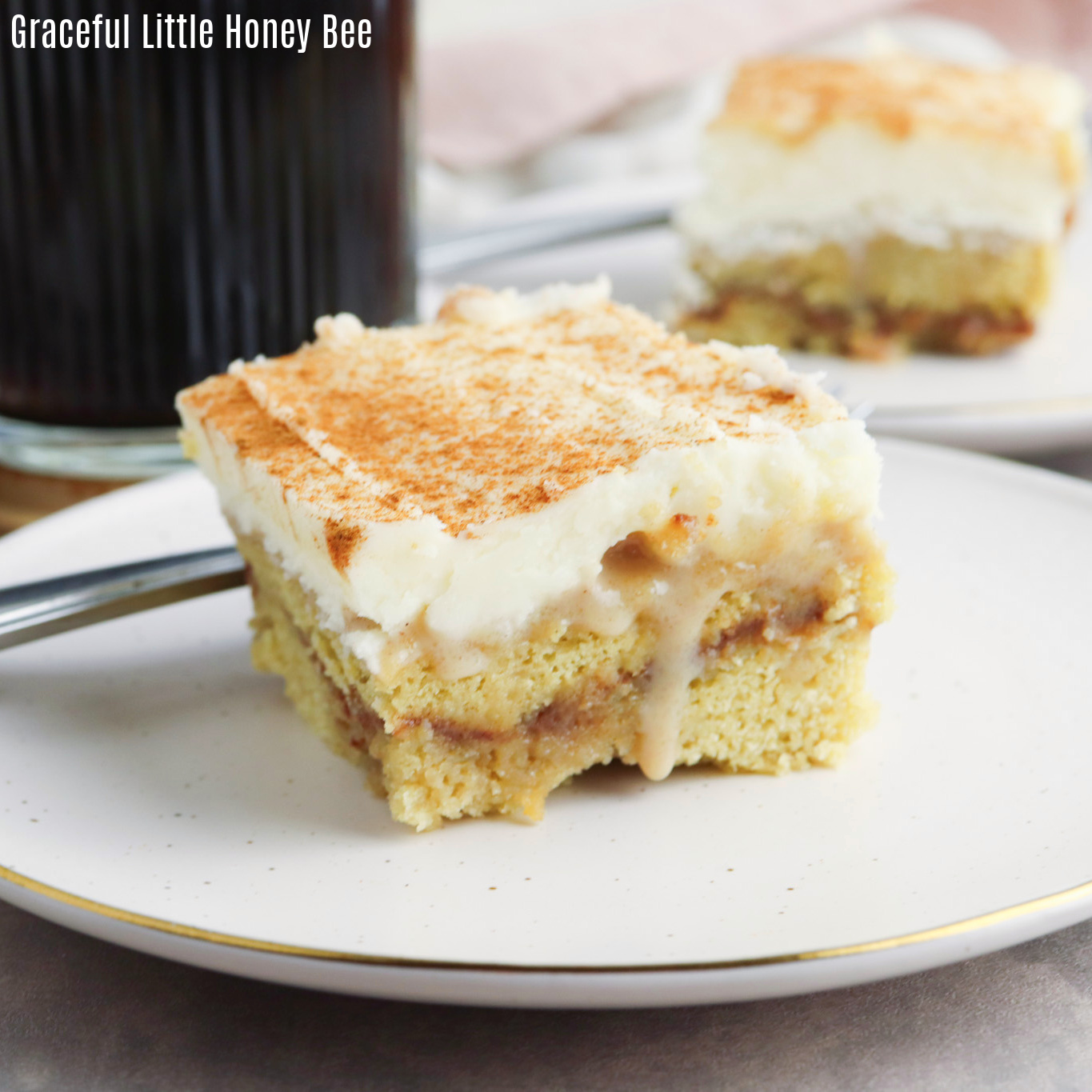 Close up view of a cinnamon roll poke cake on a white plate.