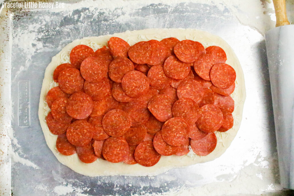 Pizza dough topped with pepperoni.
