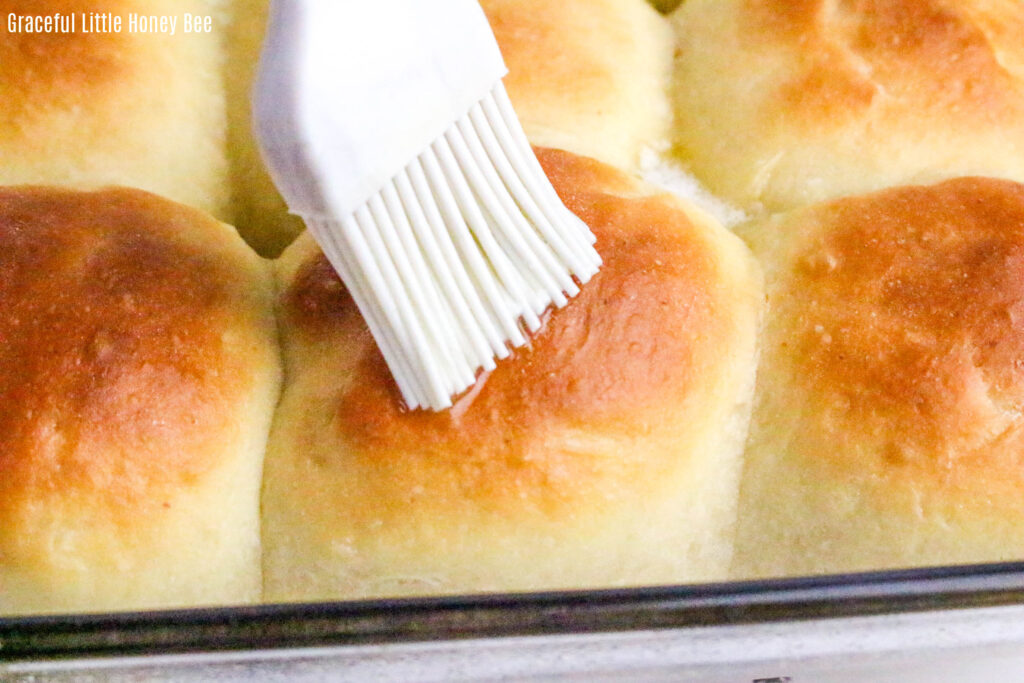 Golden brown rolls being brushed with melted butter.
