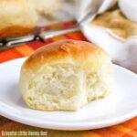 Side view of a dinner roll on a white plate.