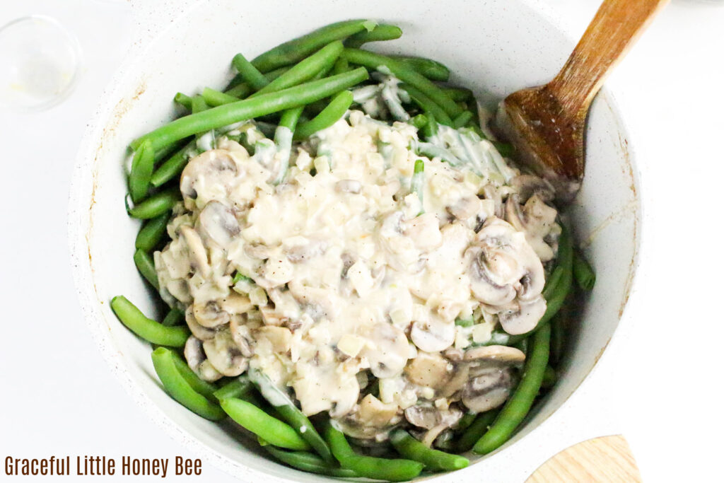 Fresh green beans in mixing bowl topped with mushrooms sauce.