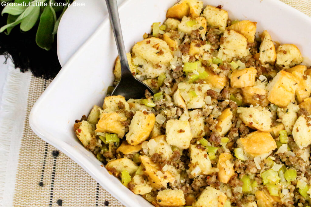 Aerial view of Sage and Sausage Stuffing in a white baking dish with a spoon inserted.