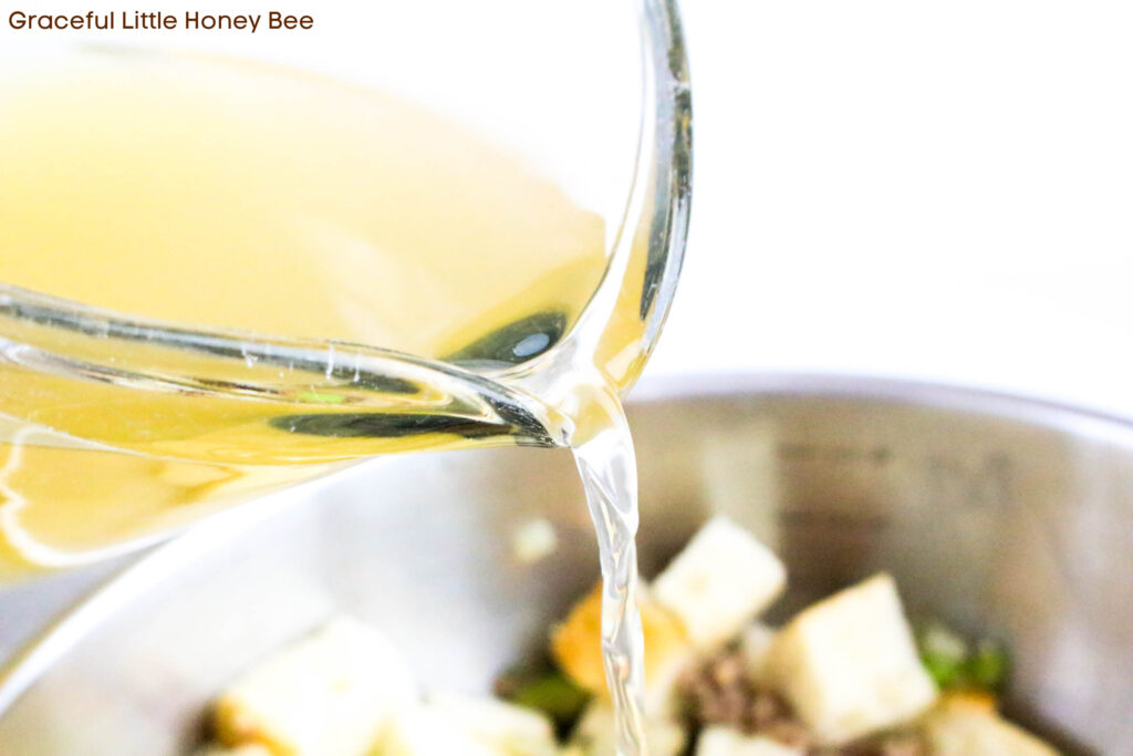 Chicken broth being poured over stuffing.