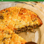 Cheeseburger pie in glass pie dish with one slice removed.