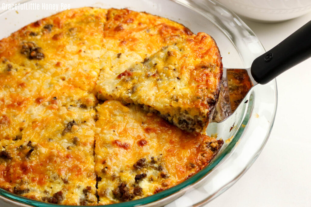 Impossible Cheeseburger Pie in a glass pie dish with a slice being removed.