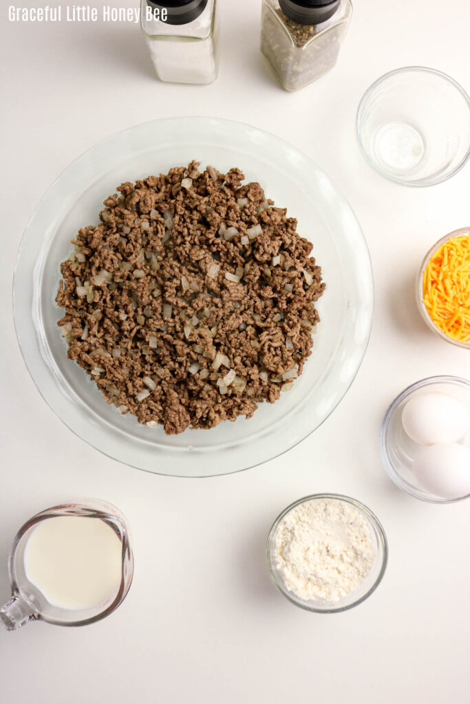 Aerial view of cooked ground beef in glass pie dish.
