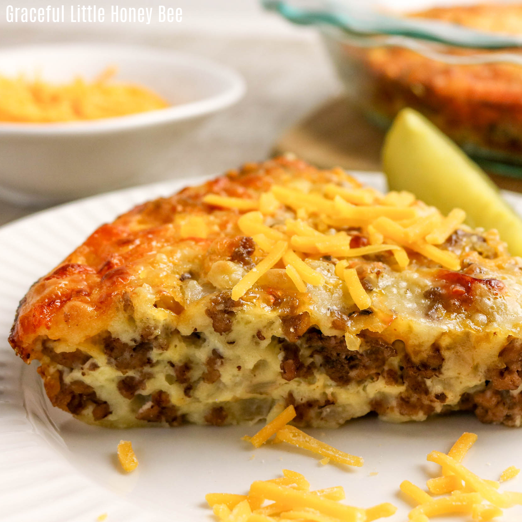 A slice of Cheeseburger Pie on a white plate with a pickle and fork.