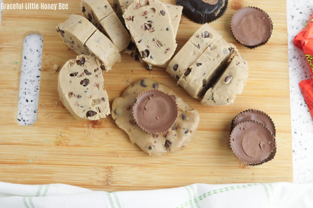 Cookie dough sliced into sections with a Reese's cup on top of one.
