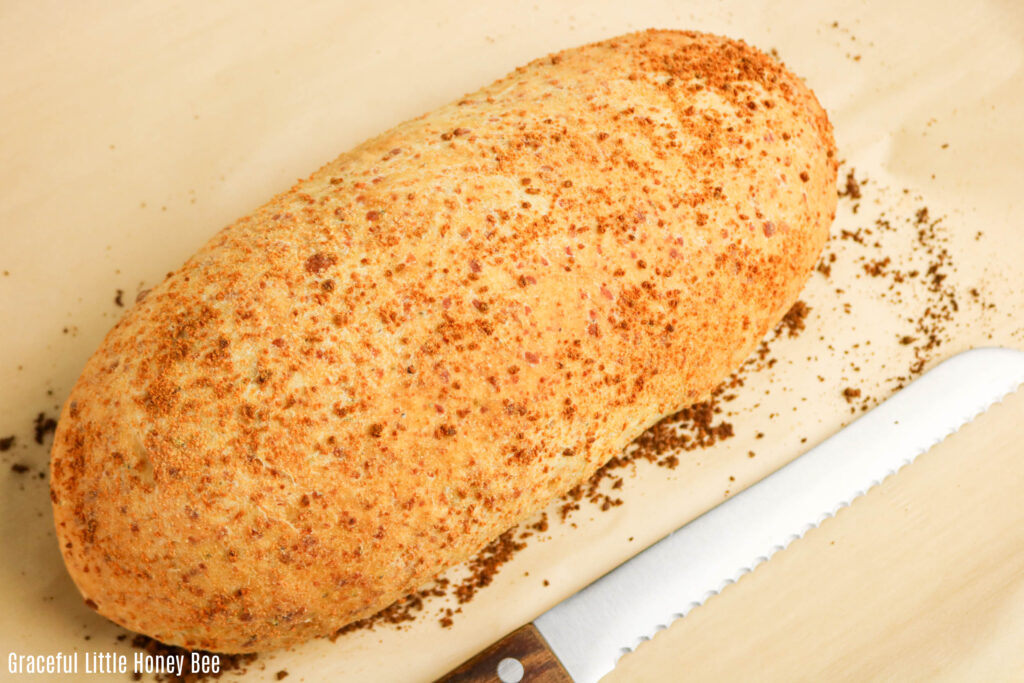Golden brown Parmesan Oregano Bread sitting on a counter with a knife next to it.