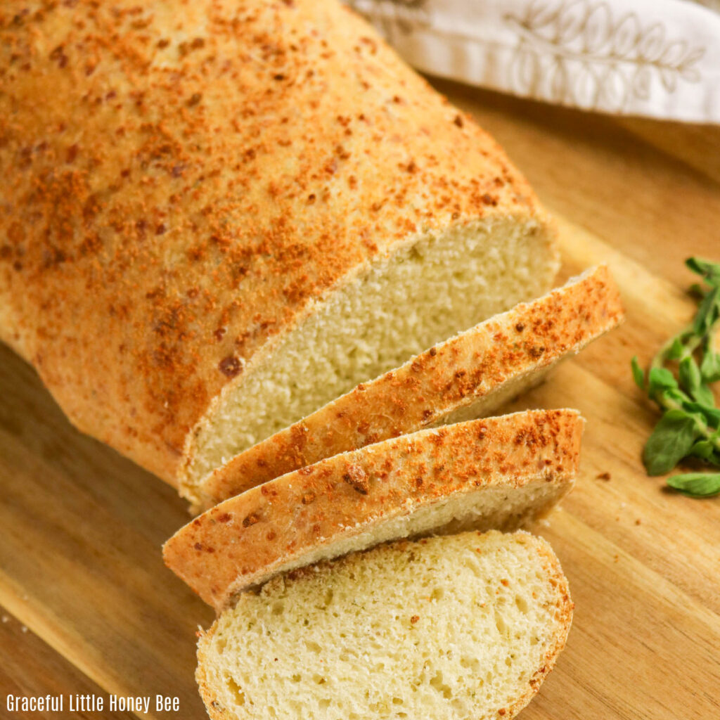 Parmesan Oregano Bread sitting on a cutting board with several slices.