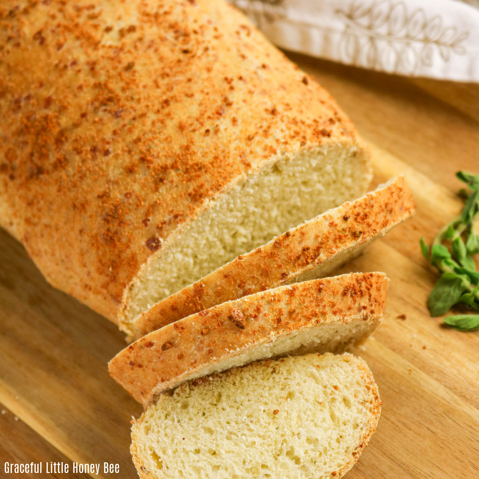 Parmesan Oregano Bread sitting on a cutting board with several slices.