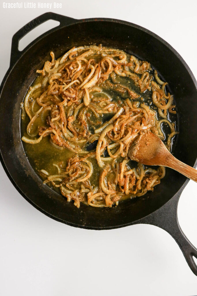 Onions being sauteed in a cast iron pan.