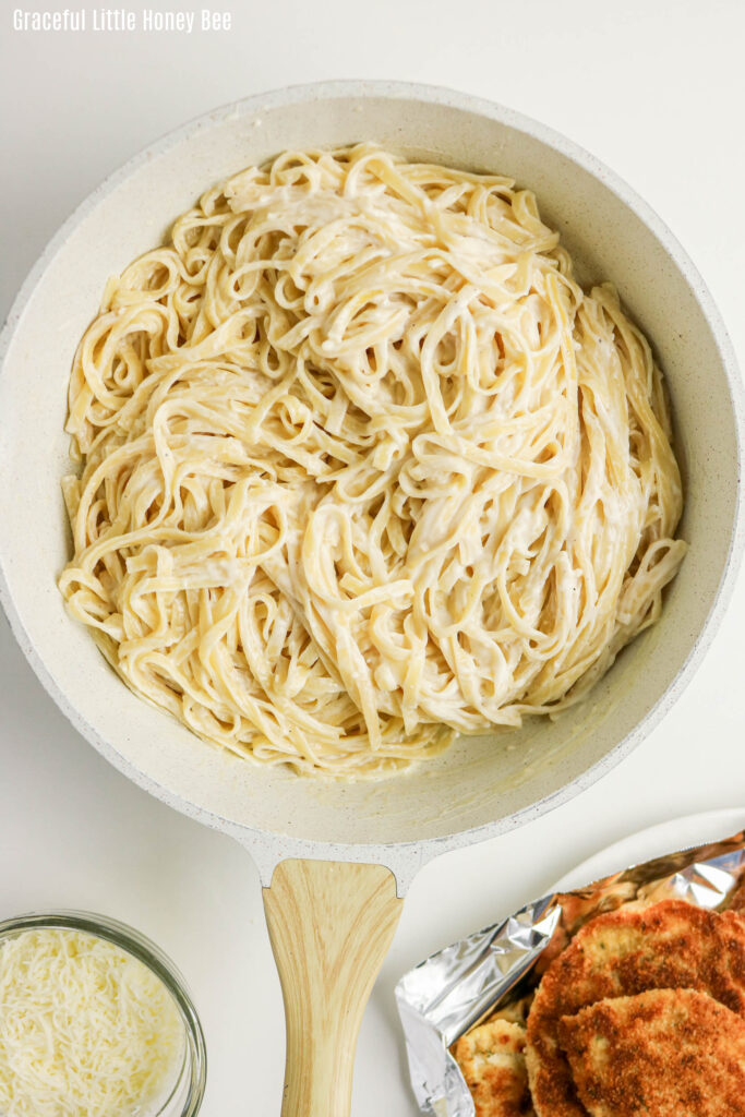 Noodles drenched in a homemade Alfredo sauce in a pot.