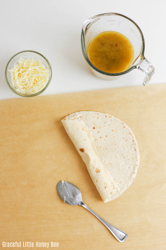 One tortilla being rolled up on a cutting board.