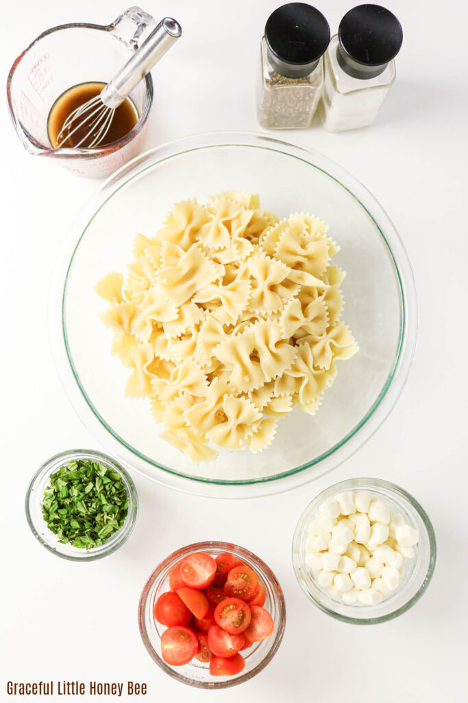 Bowl of cooked pasta with other ingredients in small bowls.
